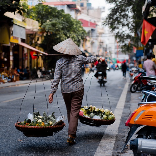 Eine Frau in Vietnam trägt Gemüse.